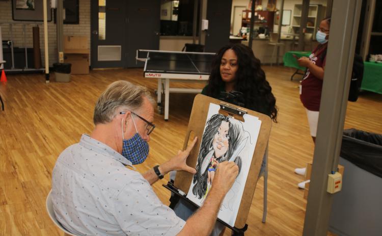 Clayon Wilson, Florida Gateway College volleyball coach, smiles as Dino Casterline draws her caricature during FGC’s first day of classes. (TONY BRITT/Lake City Reporter)