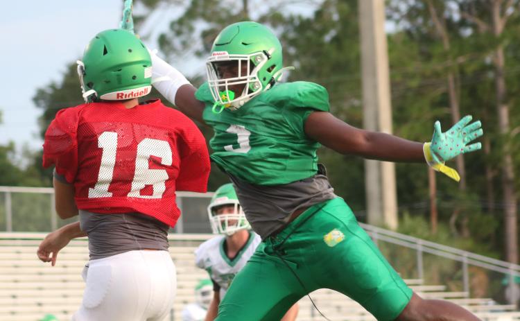 Suwannee defensive lineman Austin Smith tries to swat a pass from quarterback Bronsen Tillotson during a team scrimmage on Saturday. (JAMIE WACHTER/Lake City Reporter)