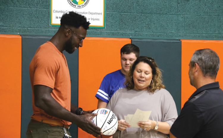 Former Gators basketball standout Patric Young (left) looks over a basketball signed by former members of the University of Florida team as Eli Stewart and Laura Lashley reminisce about Eli’s visit to a UF sports camp. (MORGAN MCMULLEN/Lake City Reporter)