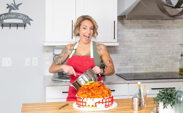 Amy Strickland puts the finishing touches on a cake, decorated as a basket of hot wings. (BRENT KUYKENDALL/Lake City Reporter)