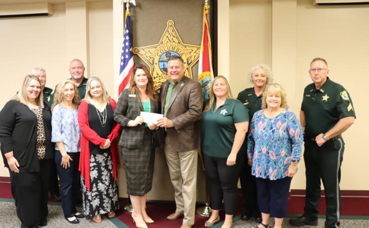 Columbia County Sheriff Mark Hunter, surrounded by other CCSO employees, presents Maria Knapp with the Florida Sheriffs Youth Ranch with a check of more than $58,000 from the agency’s annual ‘Fins-N’Pins’ fundraiser. (COURTESY/Columbia County Sheriff's Office)