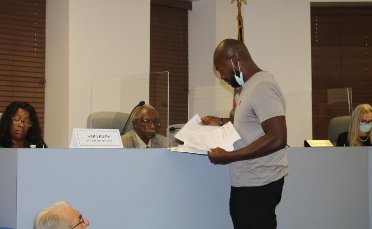 Community activist Sylvester Warren III hands out copies of his complaint to members of the Lake City Council at Tuesday’s meeting. (TONY BRITT/Lake City Reporter)
