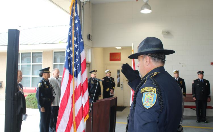 A Lake City police officer salutes the American flag Thursday at the start of the 9/11 memorial ceremony. (TONY BRITT/Lake City Reporter)