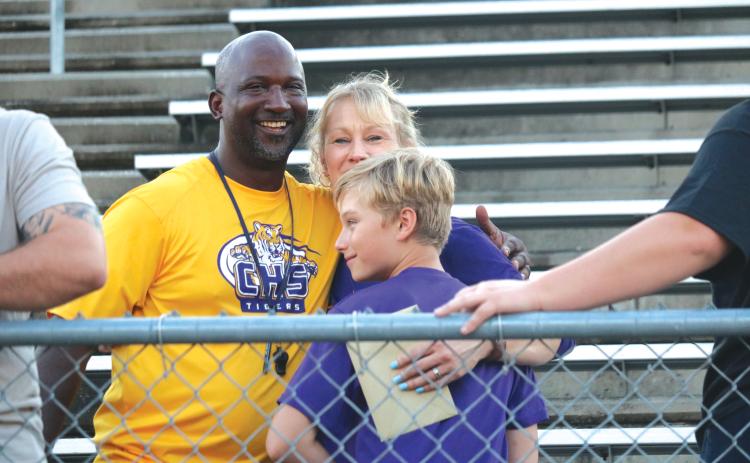 Columbia High School football head coach Demetric Jackson (left) hugs Crystal and Fisher Hair Wednesday afternoon at Tiger Stadium at a memorial service for Skipper Hair. (JORDAN KROEGER/Lake City Reporter)