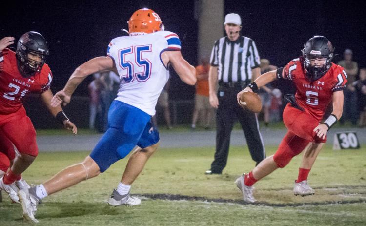 Fort White quarterback Clayton Philpot evades pressure from Branford linebacker Devin Mosley on Friday night. (CHRISTINA FEAGIN/Special to the Reporter)