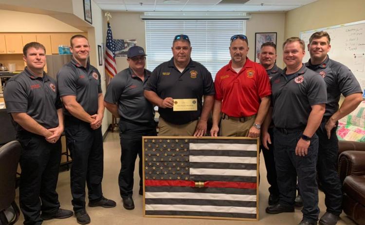 Suwannee County Fire Chief Eddie Hand (center) and Division Chief Matt Garbett present the Lake City Fire Department with a fire hose flag in memory of Chief Randy Burnham. (COURTESY)