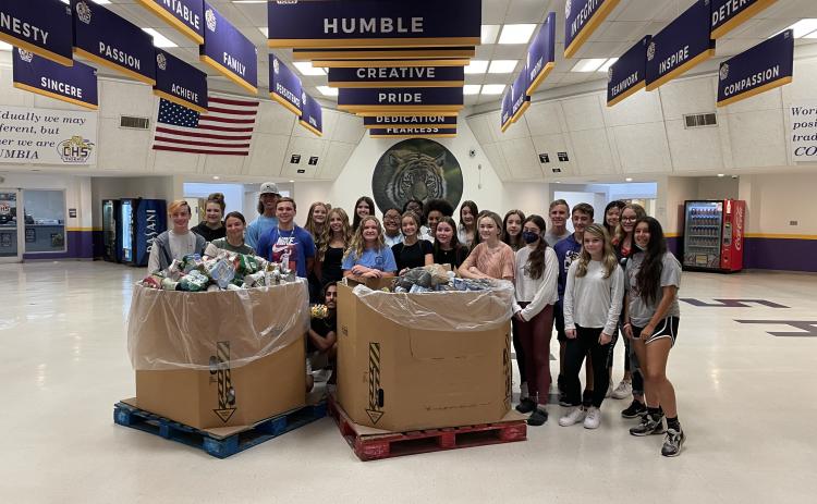 Students at Columbia High School gather around a pair of boxes containing donated canned and dry foods to be given to charity. (COURTESY)