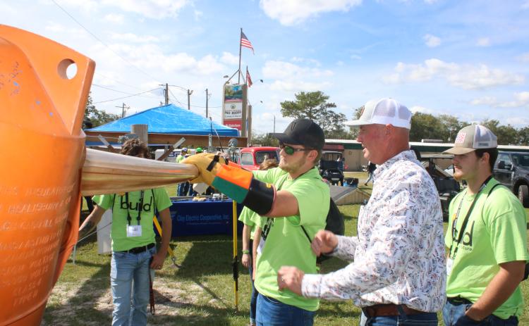 Ethan Humphries (center), a Branford High School student, uses gloves while getting tips from Eric Crawford, a Clay Electric line supervisor, during Wednesday’s Build My Future event. (TONY BRITT/Lake City Reporter)