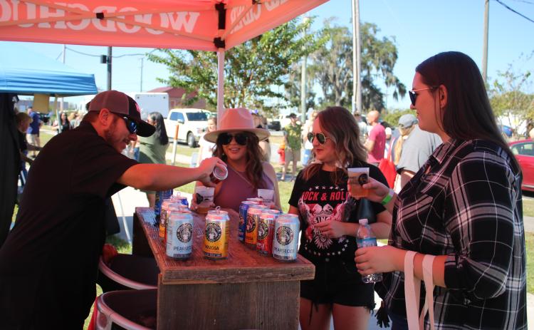 Derek Nelson (from left), of Woodchuck Hard Cider, pours a sample for Stacey Hentzelman, Britney Thrasher and Ava White. (TONY BRITT/Lake City Reporter)