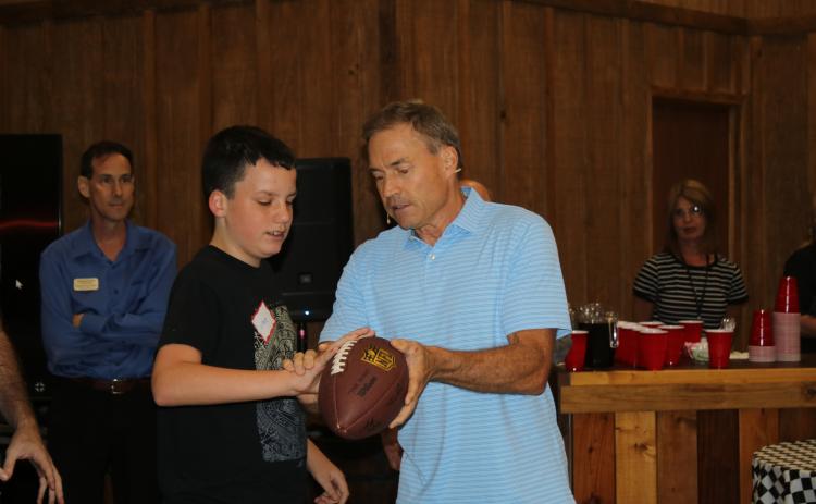 Lucas Gollery (left) gets a lesson from Jeff Kemp on how to hold a football properly. (TONY BRITT/Lake City Reporter)