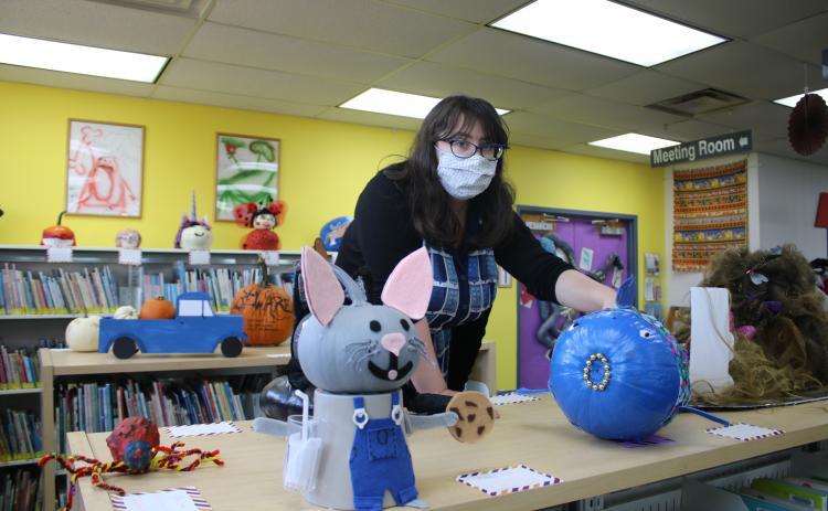 Emma Miles, Columbia County Public Library Youth Services Programs Specialist, aligns decorated pumpkins in the Youth Services Department at the main branch of the Columbia County Public Library on Tuesday afternoon. (TONY BRITT/Lake City Reporter)
