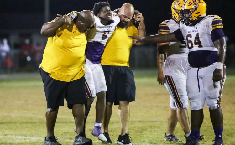 Columbia’s Tray Tolliver is helped off the field by defensive line coach Mark Campbell and co-defensive coordinator John Woodley during last Friday’s game against Madison County. (BRENT KUYKENDALL/Lake City Reporter)