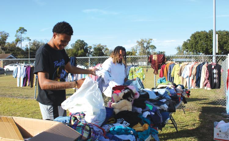 D’Andre Jefferson (left) and Thomas Williams sort through clothes and other goods Wednesday. (TONY BRITT/Lake City Reporter)
