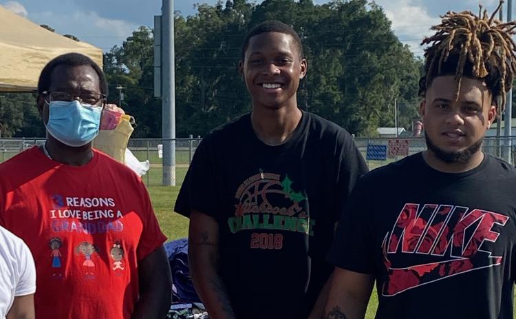 Dr. Tommy Randolph (from left), D’Andre Jefferson and Thomas Williams pose at last year’s clothing drive. (COURTESY)