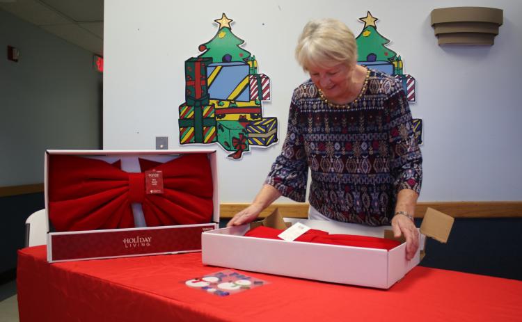 Christmas Dream Machine founder and director Meally Jenkins opens up boxes of giant bows as part of her preparations for this year’s event at 1445 SW Main Boulevard. (TONY BRITT/Lake City Reporter)