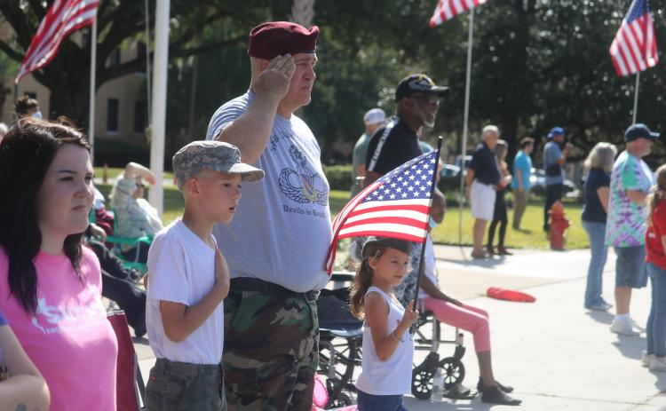 Liam Ambrose (from left), 10, U.S. Army veteran Harrison Ambrose and Bailee Ambrose, 7, stand as the Columbia High School band plays the National Anthem during Thursday’s Veterans Day parade in Lake City. (TONY BRITT/Lake City Reporter)