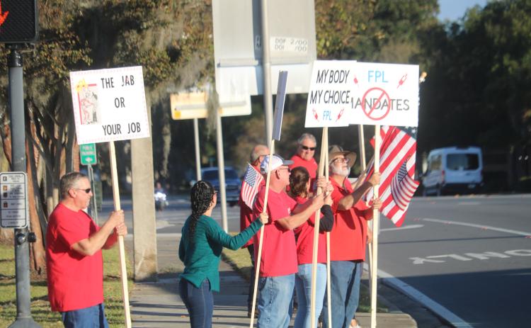 FPL employees and their families protest on the corner of Duval Street and Marion Avenue Wednesday afternoon over vaccine mandates at Florida Power and Light. (TONY BRITT/Lake City Reporter)