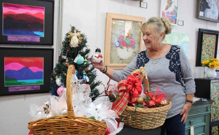 Cindy Sleezer checks out a snowman ornament at the Gateway Art Gallery. (TONY BRITT/Lake City Reporter)