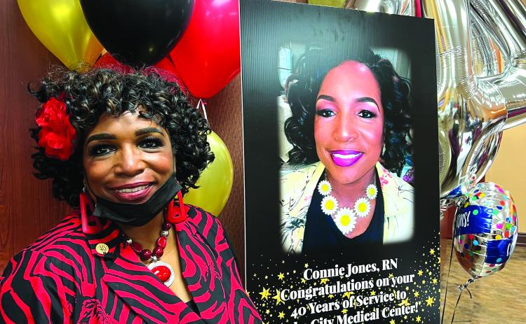 Connie Jones smiles next to a sign honoring her 40 years working at Lake City Medical Center. (COURTESY)