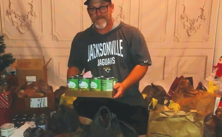 John Cole III, CEO of Saving Our Children, shows off the donated food items that will be given out to local families on Nov. 20. (TONY BRITT/Lake City Reporter)