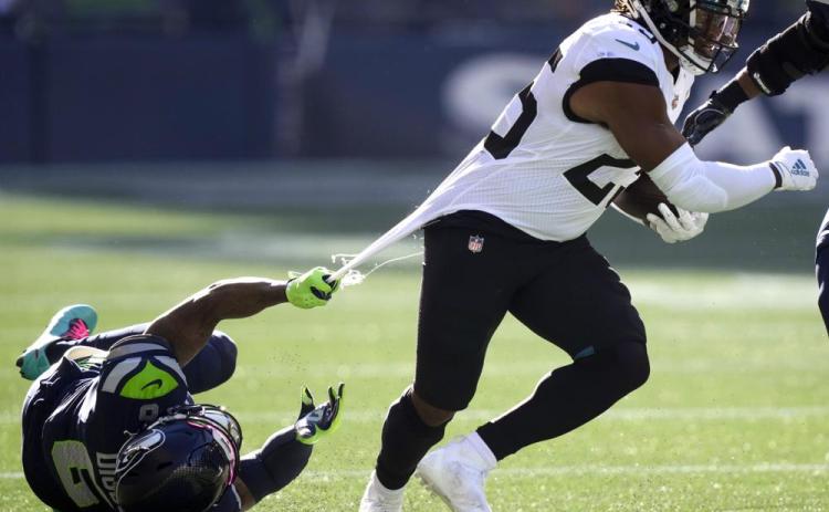 Jacksonville Jaguars running back James Robinson, right, is grabbed by his jersey by Seattle Seahawks free safety Quandre Diggs on Oct. 31 in Seattle. (STEPHEN BRASHEAR/Associated Press)