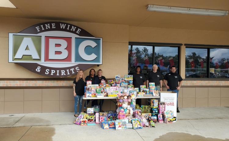 The Lake City ABC Fine Wine & Spirits employees Evelyn Alexander (from left), Sharde Chairs, Teresa Sullivan, Annettee Baker, Tom Stauffer and Chris Moll stand near the toys they purchased for the Toys For Tots program after a recent toy drive. (COURTESY)