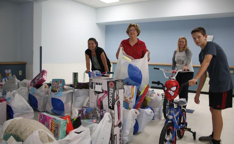 Christmas Dream Machine volunteers Jennifer Munroe (from left), Janet Stanford, Angela Towns and Walker Munroe, organize toys for the Christmas Dream Machine Toy Distribution which took place Sunday afternoon. (TONY BRITT/Lake City Reporter)