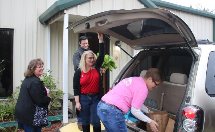 Tammy Sarber (clockwise from left), Chris Walters, Sadie House and Amy Johnson load food into a client’s van during the Christian Service Center annual Christmas Basketball give-away Monday morning. (TONY BRITT/Lake City Reporter)