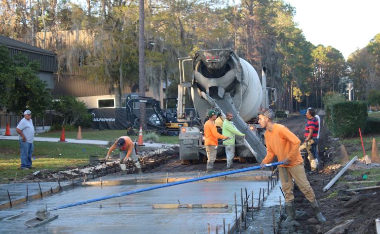 Construction workers pour and level cement near the Florida Gateway College’s Teacher Academy Building Monday afternoon. Pedestrian walkways around campus are being improved as part of a $380,000 construction project. (TONY BRITT/Lake City Reporter)