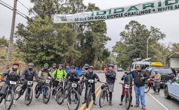 Bikers participating in the 2022 IDIDARIDE pose underneath a banner marking the event. More than 300 participants rode through the off-road courses set up for the 50-mile challenge. (COURTESY)