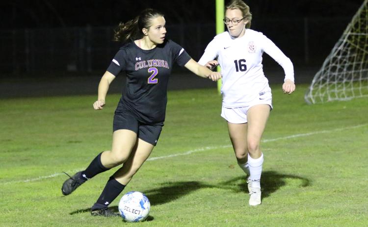 Columbia’s Hannah Dicks looks to pass to a teammate as Leon’s Emerson Jones rushes over to defend during Friday’s match. (MORGAN MCMULLEN/Lake City Reporter)