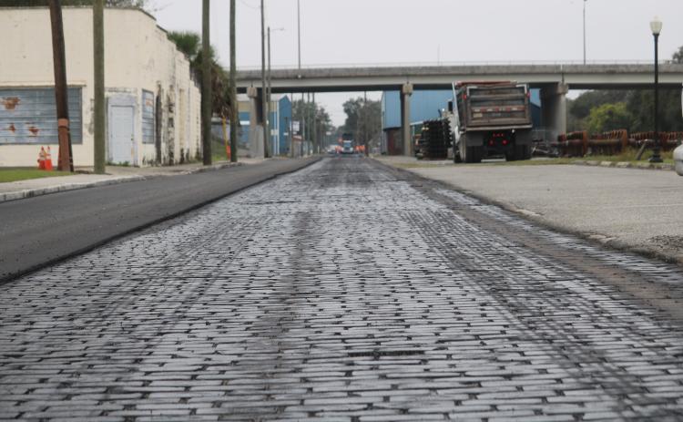 A layer of sealant covers brick pavers on Northwest Railroad Street on Wednesday afternoon as Anderson Columbia Construction Company workers resurface the roadway. (TONY BRITT/Lake City Reporter)