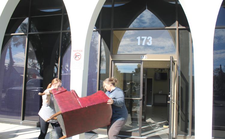 Lake City Customer Service Manager Katrina Medearis (left) and Brandy McGhin, city customer service coordinator, move furniture into the Millennium Bank building Thursday afternoon. (TONY BRITT/Lake City Reporter)