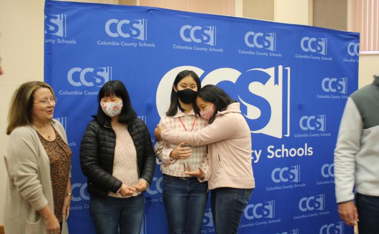 Cindy Kim (center) gets a hug from her sister, Arienna, alongside their mother, Ae-yun Shin. (TONY BRITT/Lake City Reporter)