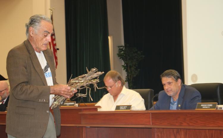 Tom Cunilio (from left), representing the Center of Sustainable Agroforestry, provides Columbia County commissioners Robby Hollingsworth and Toby Witt, with samples during Thursday’s night’s commission meeting as he requested funding for a a field day showcasing energy crops. (TONY BRITT/Lake City Reporter)