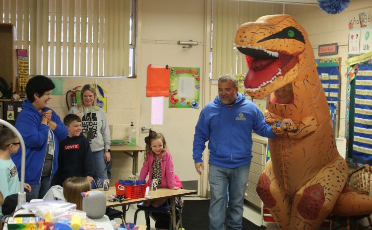 Roger Little (right), Eastside Elementary School principal, holds the hand of ‘Trixie The T-Rex’ as he introduces her to Terry Brewer’s kindergarten class. (TONY BRITT/Lake City Reporter)