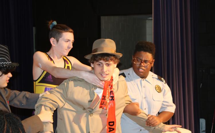 Columbia High School student Kaiden Hodson is grabbed by Colin Jolliffee and Schmari Lockley during Wednesday’s dress rehearsal for the ‘Murder at the Orient Express’ mystery dinner theater production scheduled for Friday night. (TONY BRITT/Lake City Reporter)