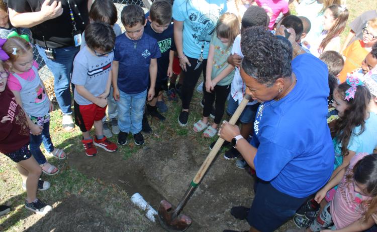 Scharlotte Stewart, Eastside Elementary School lead custodian, uses a shovel to cover a time capsule at the base of the school sign on Tuesday, 2/22/22. The capsule, which was placed by first graders, is scheduled to be open in 11 years, on 3/3/33, when the students are high school seniors. (TONY BRITT/Lake City Reporter)