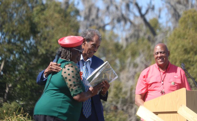 Lelia Williams (from left) is hugged by Rev. Herman Grant as Philip Mobley looks on during the Richardson Historic Marker celebration. Grant presented Williams with a plaque of appreciation for her support in helping get the historic marker for Richardson High School. (TONY BRITT/Lake City Reporter)