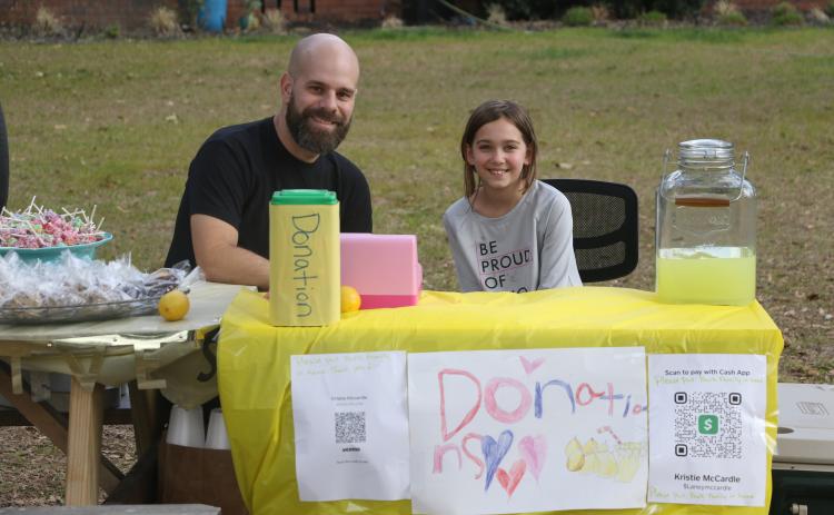 Corey Burk (left) and Lexi Mccardle sit behind Lexi’s lemonade stand Thursday afternoon. (MORGAN MCMULLEN/Lake City Reporter)