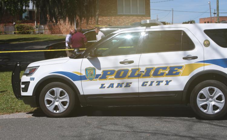 LCPD detectives huddle up in a parking lot near Lake DeSoto Monday morning following a report of two dead bodies in a vehicle. (JAMIE WACHTER/Lake City Reporter)