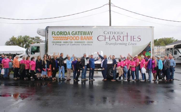 Members and volunteers with Catholic Charities put their hands on a refrigerated food truck bought by the organization in February. (TONY BRITT/Lake City Reporter)