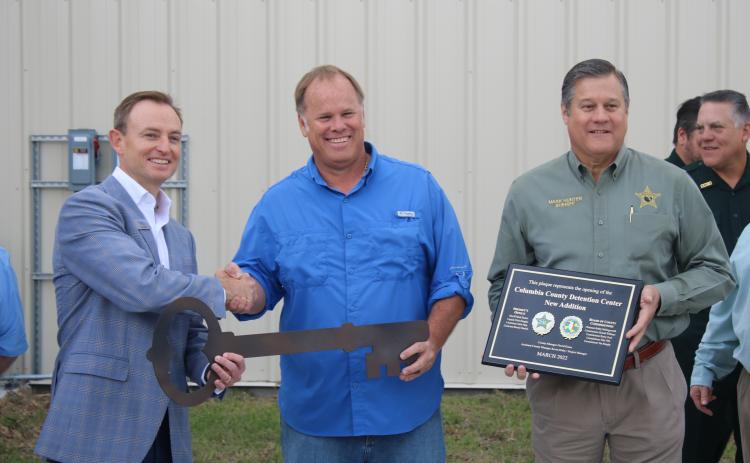 Jay Smith, Ajax Building Company vice president (from left), accepts a ceremonial key from Robby Hollingsworth, Columbia County Commission chairman, as Sheriff Mark Hunter holds a plaque noting the completion of the Columbia County Detention Facility addition. (TONY BRITT/Lake City Reporter)