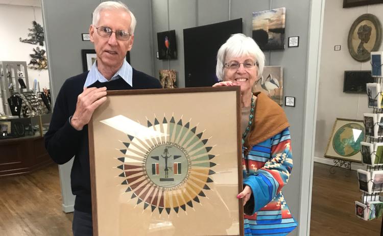 Jim Riley, past president of the Art League of North Florida/Gateway Art Gallery, receives one of the donations of the Harter Trust from Rose Pavey, Administrator. This piece is a Navajo sand painting and will be in the exhibit. (COURTESY)