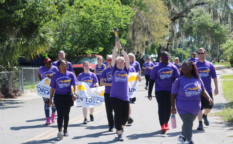 A participant in Tuesday’s Law Enforcement Torch Run for Special Olympics hoists the torch up above her head. (TONY BRITT/Lake City Reporter)