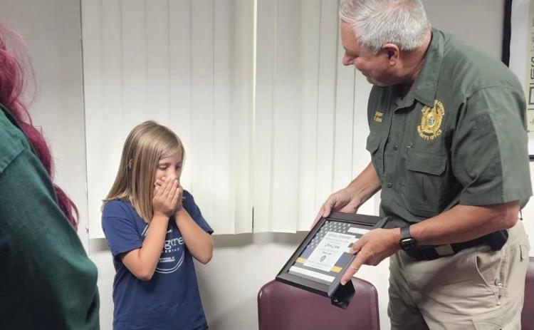 Olivia Cauley, 9, receives an ‘official superhero’ certificate from Suwannee County Sheriff Sam St. John on Tuesday for her actions on May 14 to assist her mother, Stephanie, following a medical emergency. (COURTESY)