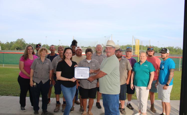 Columbia County Tourist Development Council Executive Director Paula Vann presents Clint Pittman, the county’s Landscapes and Parks director, a certificate Tuesday morning at Southside Sports Complex for helping advance tourism in the county as they are joined by TDC and park staff. (TONY BRITT/Lake City Reporter)
