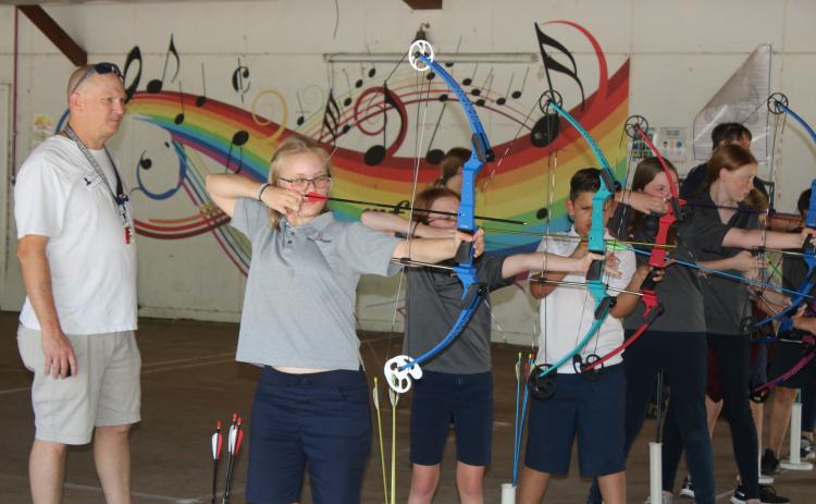 Marta Priller, 11, a member of the Belmont Academy Elementary archery team prepares to fire an arrow while assistant coach Keith Williams looks on. (TONY BRITT/Lake City Reporter)