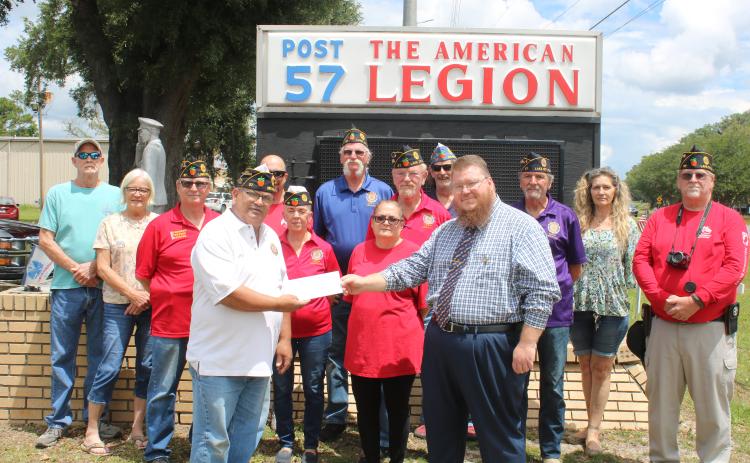 Rick Cabrera, American Legion Post 57 commander (front row, from left) gives Chris Esing a contribution to aid in the purchase of a War on Terror memorial monument on Friday afternoon. Other Post 57 members in attendance were: Jim Taylor (middle row, from left), Rustyann Brown, Laura Cabrera, Bill Huggins, Jim Reherman and Thomas Wilcutts; Steve Cox (back row, from left), Debbie Cox, Michael Ziegler, Thomas Johnson, Mitchell Cooper and Dianna Cooper. (TONY BRITT/Lake City Reporter)