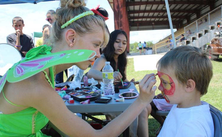 Faith Ingram (left), of the Columbia High School drama club, adds the finishing touches to Xavier Boutwell’s face paint at the Kiwanis Kids Day. (TONY BRITT/Lake City Reporter)